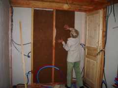 Margaret pushing wood fibre insulation into the bathroom partitions.  This is primarily for sound insulation.